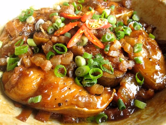 Hành khô cho vào nướng cháy xem rồi bóc vỏ và đập dập. Cho cá, hành nướng và phần đầu hành vào nồi đun lửa lớn khoảng 5 phút rồi thêm nước cho đến khi ngập mặt cá và tiếp tục kho đến khi cá cạn gần hết nước thì cho thêm ớt xanh vào, nêm nếm lại gia vị cho vừa ăn. Đun tiếp đến khi nước kho cạn sệt lại là được. Ảnh: yeunoitro.net.