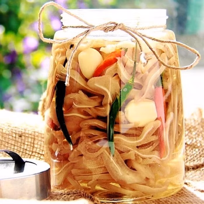Khi tai chín thì vớt ra ngâm vào nước đá để tai được trắng và giòn. Pha dấm, đường, nước mắm, nước cho vừa miệng rồi nấu sôi và để nguội. Cho tai nguyên miếng cùng ớt, tỏi vào lọ và đậy kín. Khoảng 5 ngày sau là ăn được. Ảnh: Bepgiadinh.