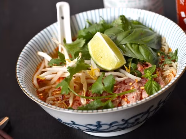  Mỳ "giả" phở: Nấu mì theo hướng dẫn trên bao bì, sử dụng một nửa gói bột nêm. Thêm vào nước dùng 1 quả chanh vắt, một thìa đường, 2 thìa nước mắm, một nhúm ớt xay. Sau đó, đổ mì với nước dùng vào bát, thêm vào vài miếng thăn bò thái thật mỏng, giá đỗ và rau sống. Ảnh: HaVietfoods.vn.
