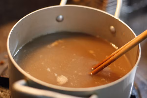 Hoa thiên lý nấu cua. Dùng dụng cụ để lọc cua sau khi xay nhuyễn để lấy nước, bỏ bã. Bắc nồi canh lên bếp đun với lửa bình thường. Cho gạch cua lên phi cho vàng với mỡ rồi đổ vào nồi canh đang đun, khi bắt đầu sôi thì vặn nhỏ lửa. Ảnh: yeunoitro.net.