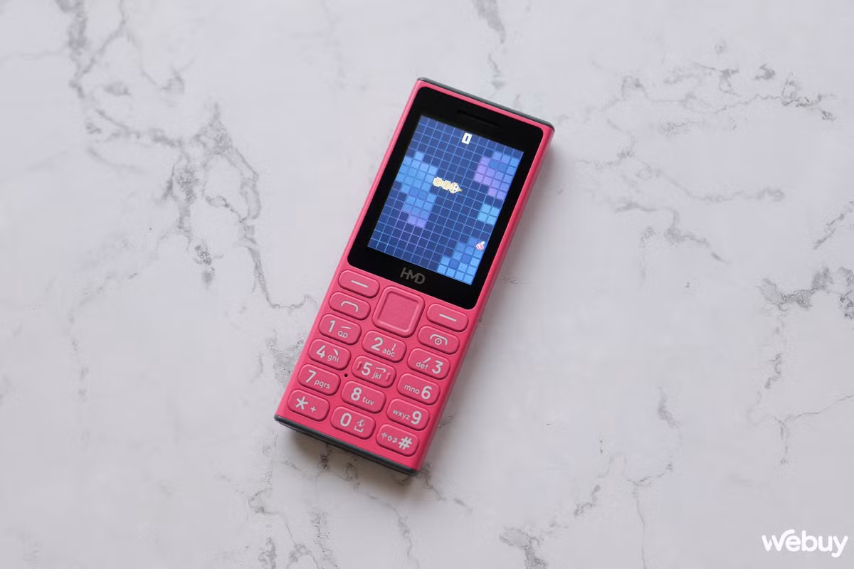 HMD 105 4G có thiết kế nhỏ gọn, với trọng lượng chỉ 92,99g và kích thước vừa phải, giúp người dùng dễ dàng cầm nắm. Màn hình 2,4 inch với độ phân giải QVGA cung cấp hình ảnh rõ ràng, mặc dù lớp kính bên ngoài dễ bị phản chiếu ánh sáng, gây khó khăn khi sử dụng dưới trời nắng gắt.