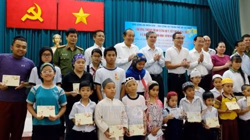 Phó Thủ tướng thường trực Trương Hòa Bình cùng các nhà tài trợ và thành viên ban tổ chức chương trình trao các suất học bổng cho con em đồng bào người Chăm trên địa thành phố. Ảnh: Thế Anh-TTXVN