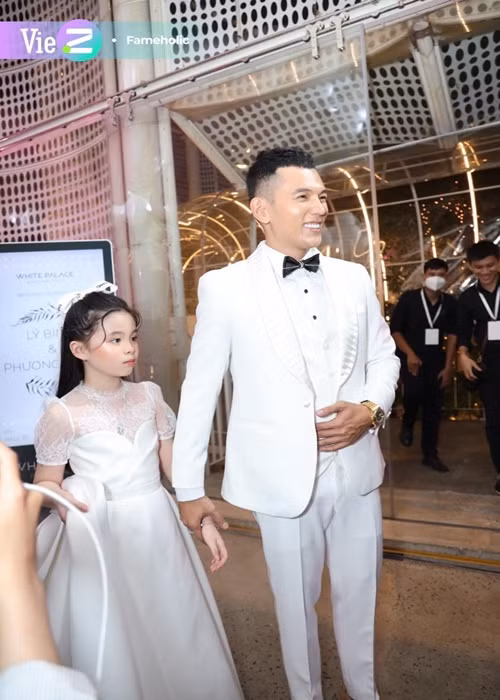Trong đám cưới, Lý Bình luôn nắm chặt tay bé Mia, che chắn Mia phía sau lưng mình, tránh ống kính và những người qua lại đông đúc. Ảnh: VietZ