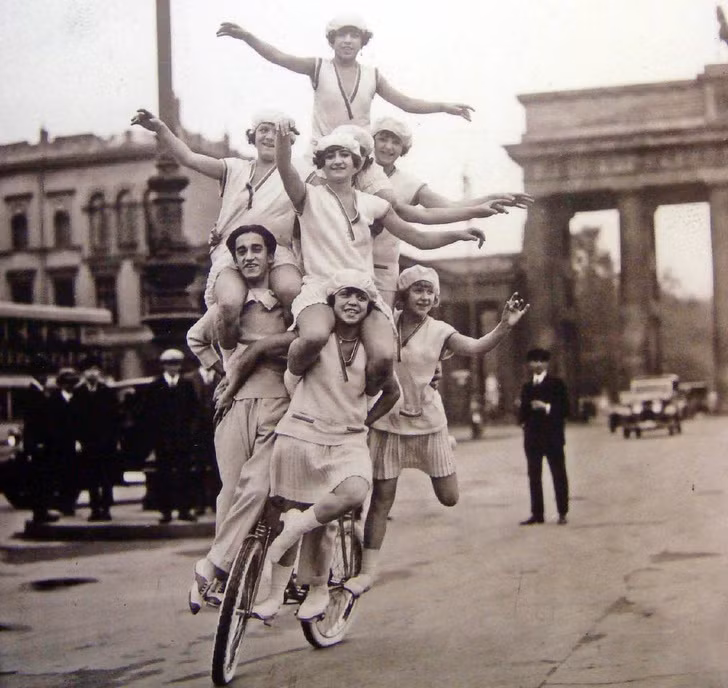 Một gia đình biểu diễn trên một chiếc xe đạp trên đường phố Berlin, Đức năm 1920. Màn trình diễn này thu hút sự chú ý của người dân xung quanh.