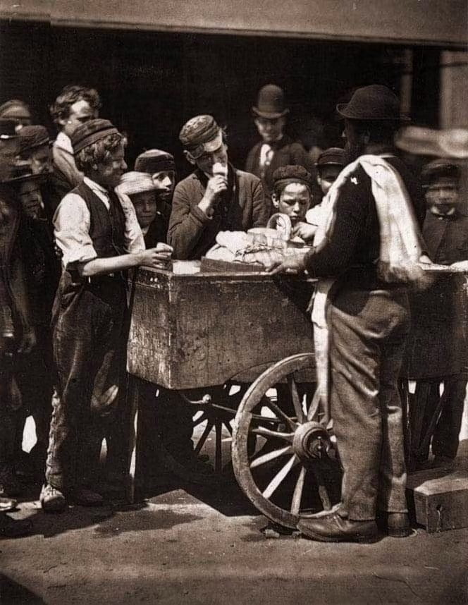 Mọi người quây quanh xe bán kém dạo ở London năm 1876. Ảnh Telegraph