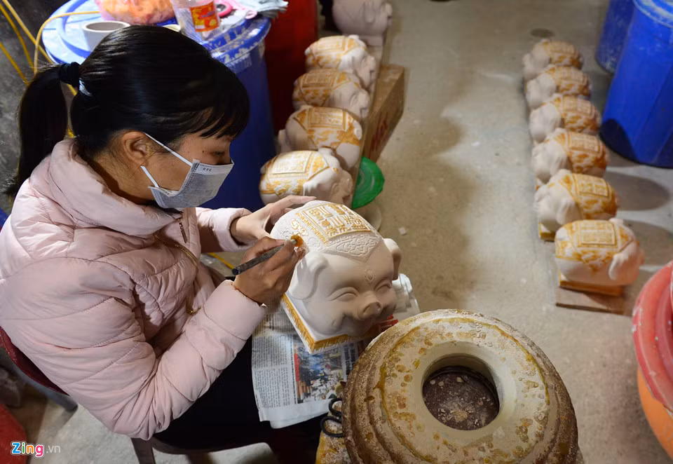 Một người thợ sẽ dùng bút bằng sáp nến để vẽ lên những hoa văn trên mình lợn. Sau đó, chúng được tráng men và nung thêm một lần nữa.