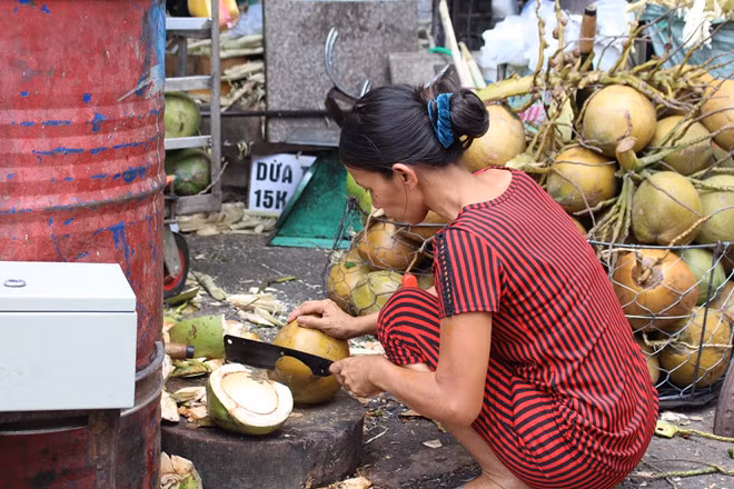 Vợ chồng anh Trình phải luôn tay, luôn chân làm việc cả ngày phục vụ nước mía và dừa lạnh cho khách hàng. Ảnh: Phúc Minh.
