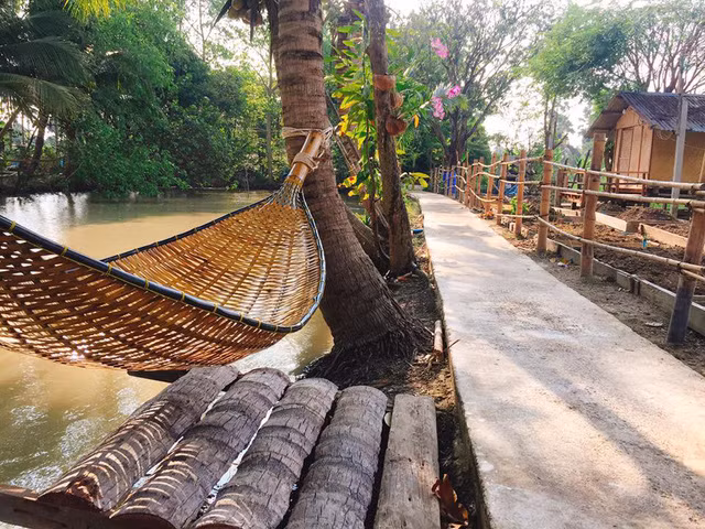 Ao phía trước nhà được mắc một chiếc võng cứng đan bằng nan tre độc đáo.