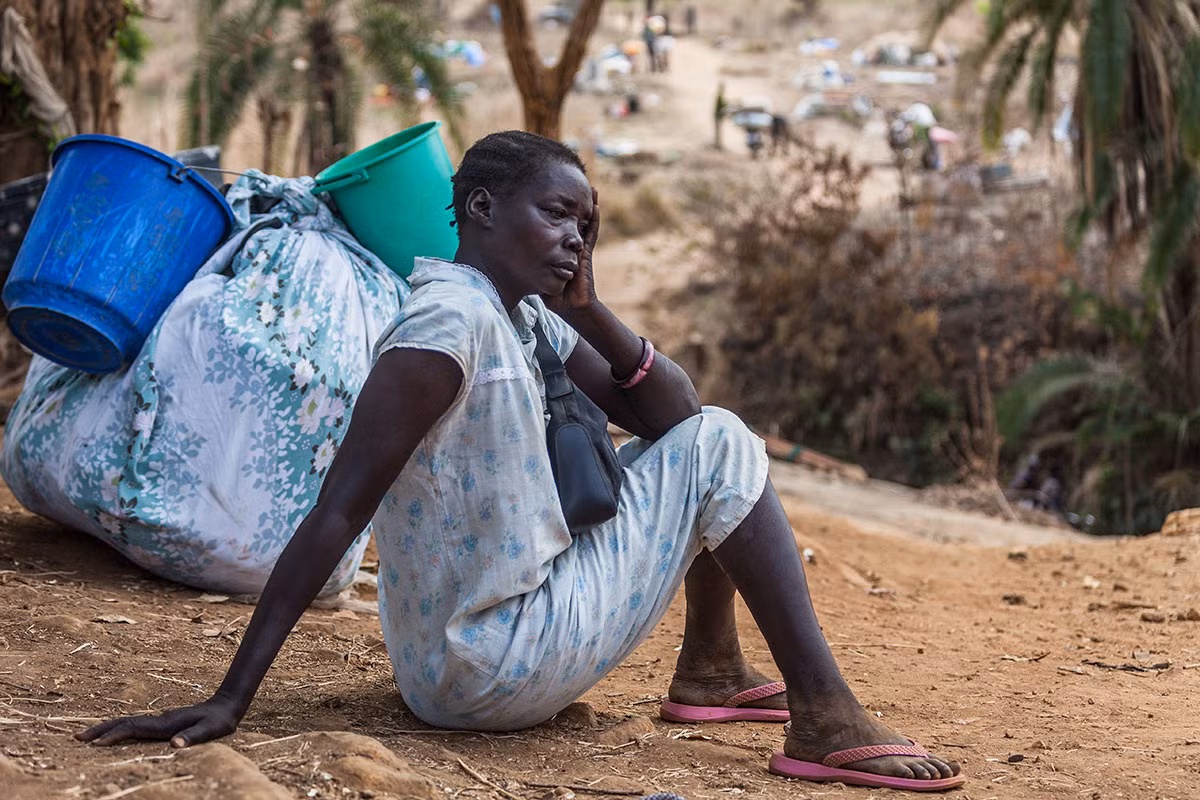 Một phụ nữ ngồi nghỉ trước khi vượt qua dòng suối Kayo để sang Uganda. Được biết, có tới 86% người tị nạn Nam Sudan là phụ nữ và trẻ em.