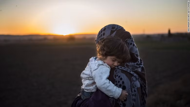Người phụ nữ Iraq bế đứa con nhỏ đang ngủ ngon lành sau khi vượt qua sông Tigris ngày 19/11.