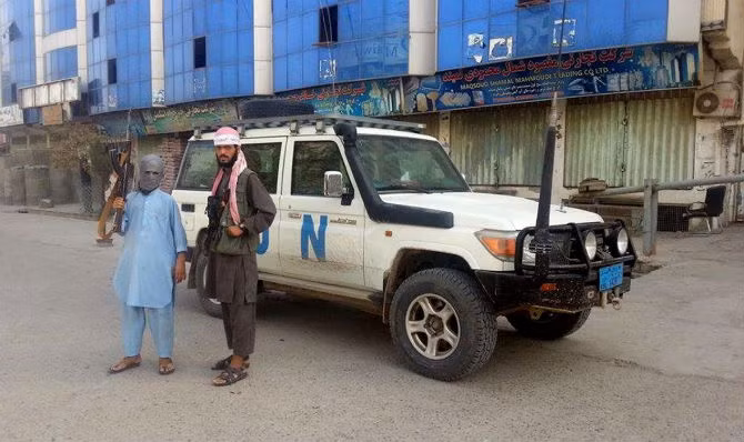 Hai chiến binh Taliban đứng gần một chiếc xe của Liên Hợp Quốc tại thành phố Kunduz.