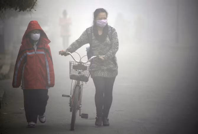 Người dân đeo khẩu trang đi trên con đường mù mịt khói bụi ở thành phố Cát Lâm, tỉnh Cát Lâm ngày 22/10/2013.