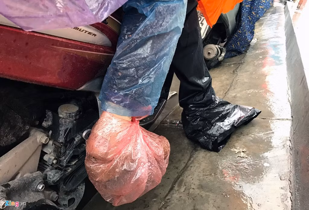 Trên tuyến đường này xuất hiện nhiều vũng nước đọng có thể gây bẩn quần, giầy, tất cho người đi xe máy. Để đối phó, một số người đã bọc nylon vào chân. Ảnh: Tiến Tuấn.