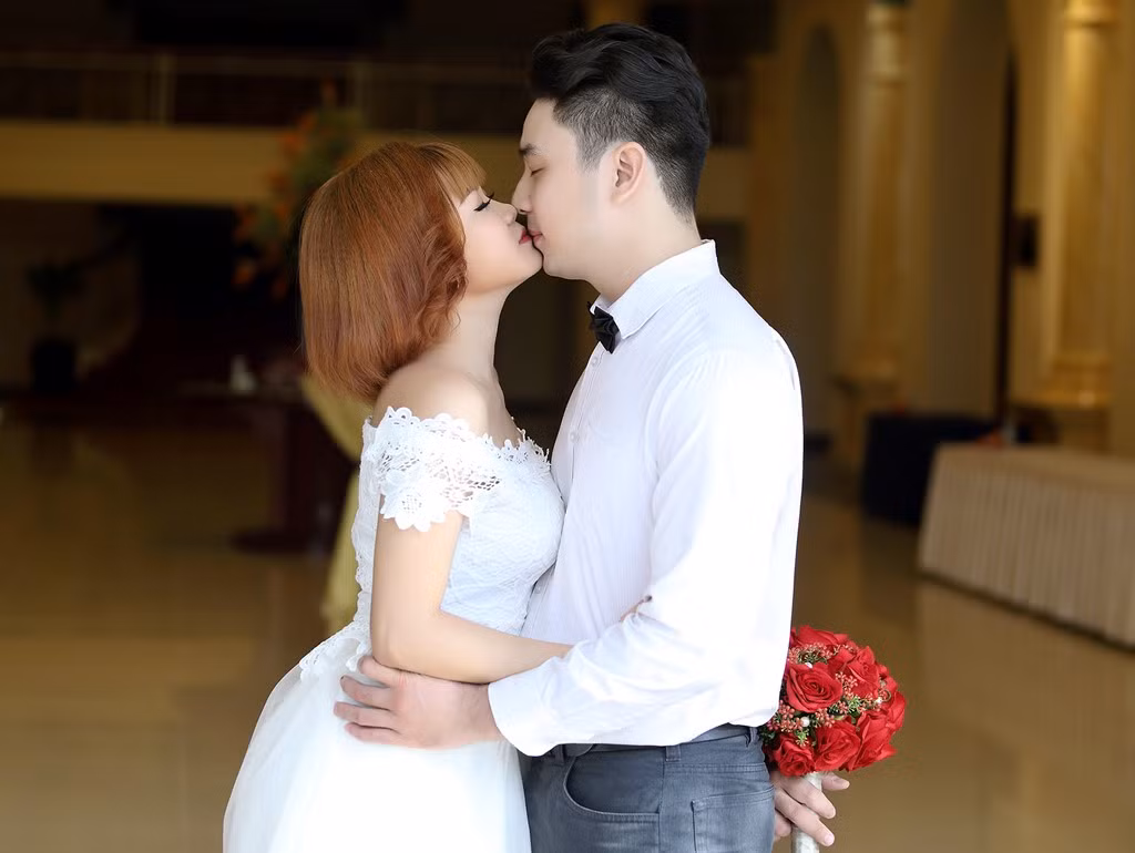 Một đôi tự nhiên chụp cảnh trao nụ hôn trước sảnh khách sạn.