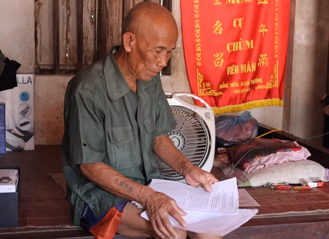 Cụ Thêm bên tập giấy tờ liên quan vụ án oan hơn 45 năm trước. Ảnh: Hoàng Lam.