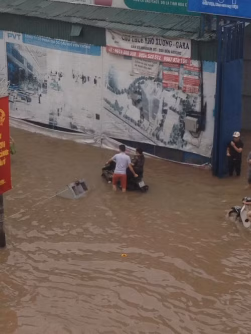 Khoảnh khắc chàng trai dắt xe cho mẹ ngồi trên yên qua chỗ ngập nước cũng lay động triệu trái tim về tình mẫu tử thiêng liêng. (Ảnh: Duy Khánh).