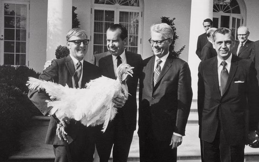 Cựu Tổng thống Richard Nixon (giữa) tươi cười đứng cạnh một con gà tây khổng lồ trước Nhà Trắng năm 1971.