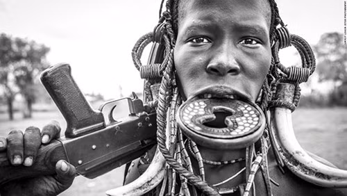 Một người phụ nữ của bộ lạc Mursi với khẩu súng trường AK-47. Trong con mắt của người Mursi, gia súc là tín hiệu đầu tiên của sự giàu có, nên với khẩu AK-47 này, họ sẽ bảo vệ tài sản của mình khỏi những kẻ cướp gia súc.