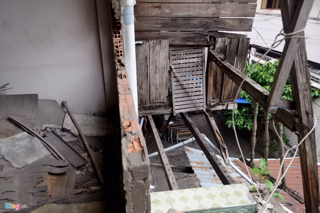 Tường của một căn hộ bị đập bỏ trở nên trống hoắc, bên ngoài lộ ra những thanh gỗ cơi nới ban công đang mục nát.
