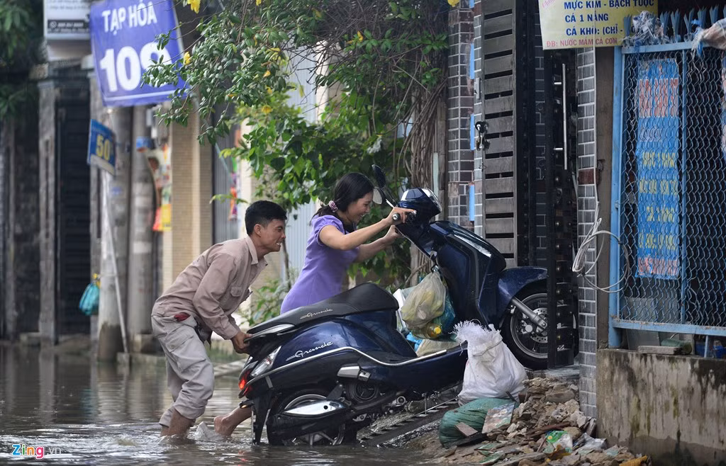 Việc dắt xe máy vào nhà trước mặt đường đầy nước, ổ gà, sỏi đá không dễ dàng như ngày thường đối với nhiều người.