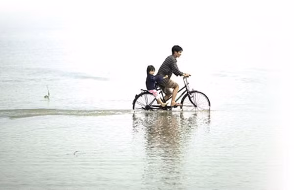 Cha và con vượt qua nước lũ.
