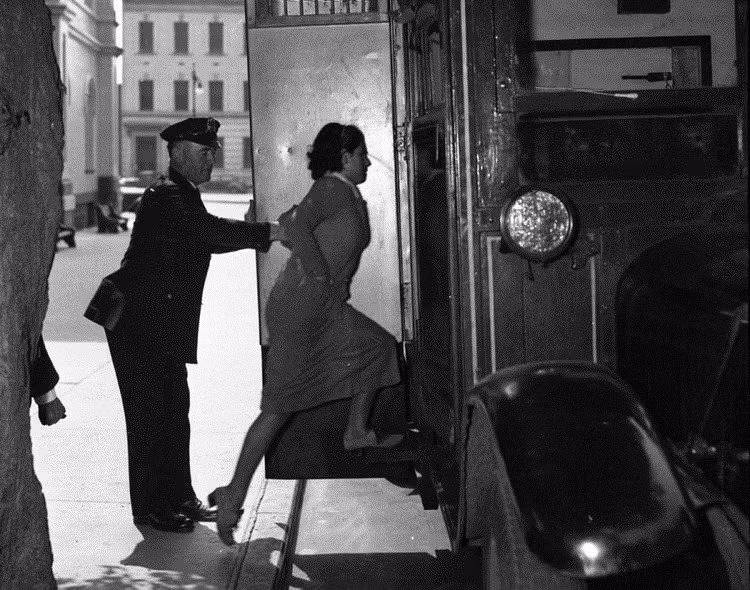 Một cảnh sát áp tải cô gái 17 tuổi tên Nancy Serville vào nhà giam năm 1935. Cô này bị cáo buộc là gián điệp cho băng đảng cướp bóc ở phố Queens.