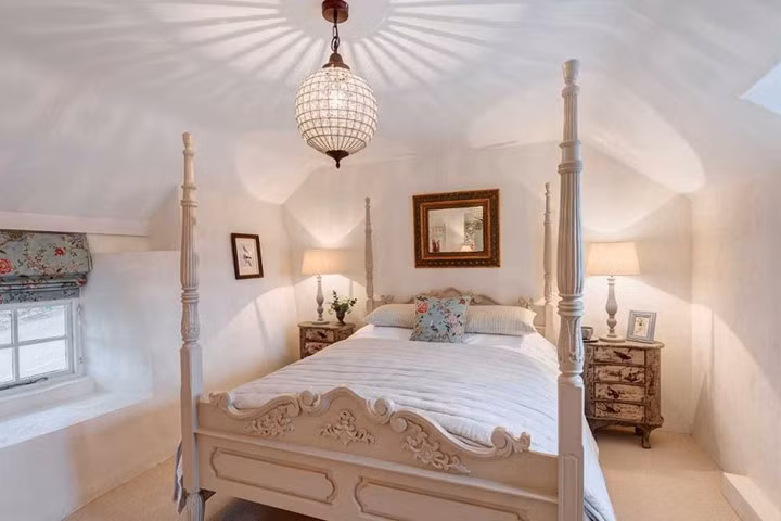 Trong phòng ngủ, có một chiếc giường lớn phong cách cổ với tủ đầu giường bằng gỗ. Tất cả các bức tường được sơn màu trắng khiến căn phòng như rộng rãi và tươi sáng hơn.