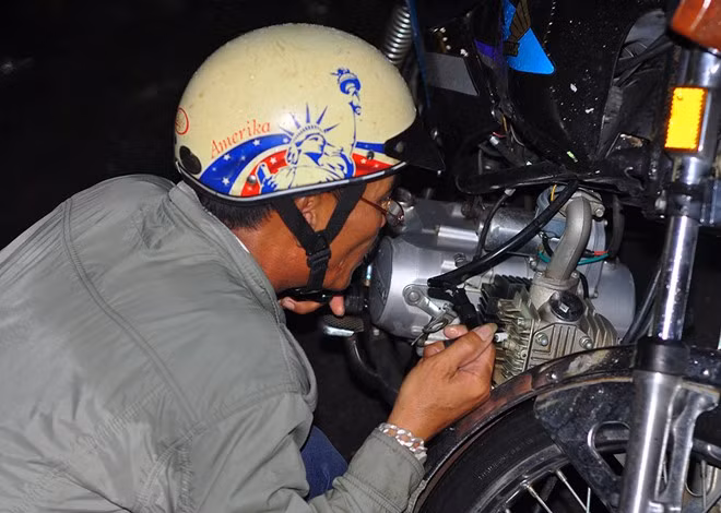 Một người đàn ông kiểm tra bộ đánh điện của xe sau khi đẩy bộ qua đoạn ngập. "Các tiệm sửa xe bên đường đều chật kín người, tôi chờ mãi mà chưa đến lượt để nên tự kiểm tra" - ông nói.