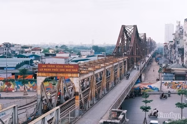 Cầu Long Biên - vẻ đẹp của thời gian bởi màu lịch sử, cái hồn cái tình thắm đượm trong khoảnh khắc của người chụp ảnh. Nhịp sống ven cây cầu Long Biên êm đềm, bình lặng. Đứng ở nơi đây, bạn sẽ có cảm giác như bắt gặp hai cuộc sống trái ngược nhau. Bên dưới gầm cầu là sự tĩnh lặng, bình yên của vùng bãi bồi thôn quê. Phía bên trên là những toà cao ốc, tiếng xe bám rít còi phá bĩnh.
