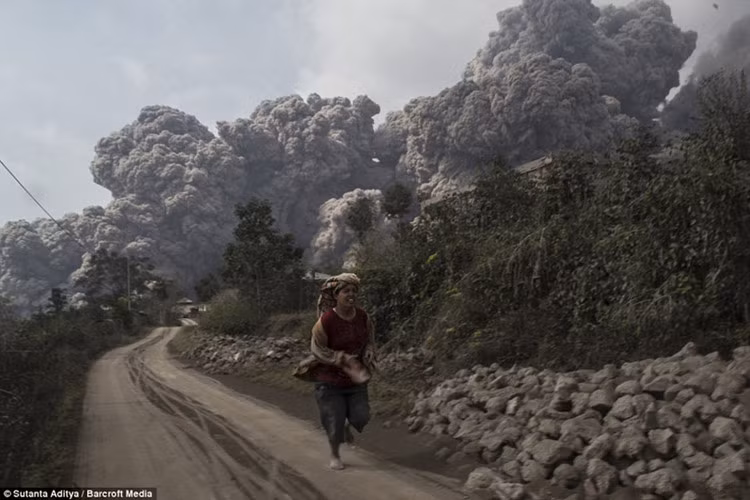 Người phụ nữ Indonesia hoảng loạn tìm cách thoát thân khỏi đám tro bụi khổng lồ, thời điểm ngọn núi lửa khổng lồ Sunabung phun trào ngày 19/6/2015.