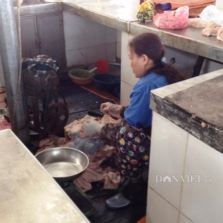 Người bán hàng đang chuẩn bị xay mỡ lợn bằng chiếc máy gỉ sắt, mỡ bẩn đen kịt bám xung quanh.
