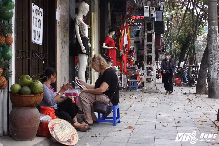 Một hàng bán ảnh (Hà Nội xưa) ngồi ép vào hiên một ngôi nhà trên phố Hàng Bông (Hoàn Kiếm, Hà Nội). (Ảnh: Tùng Lâm)