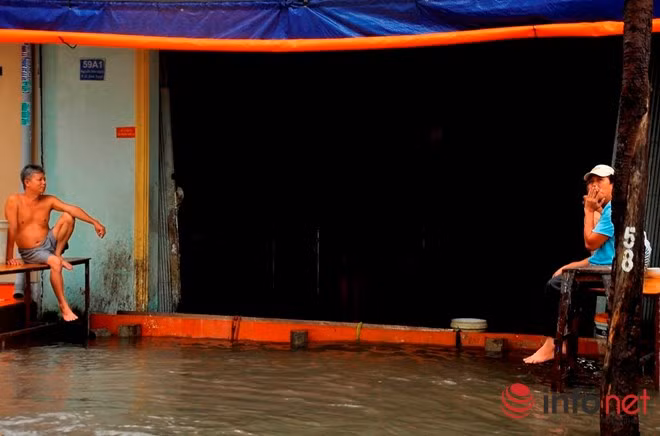 Một nhà dân bị nước vào, người dân ngồi bất lực "buông xuôi" khi không thể ngăn cản nổi dòng nước.