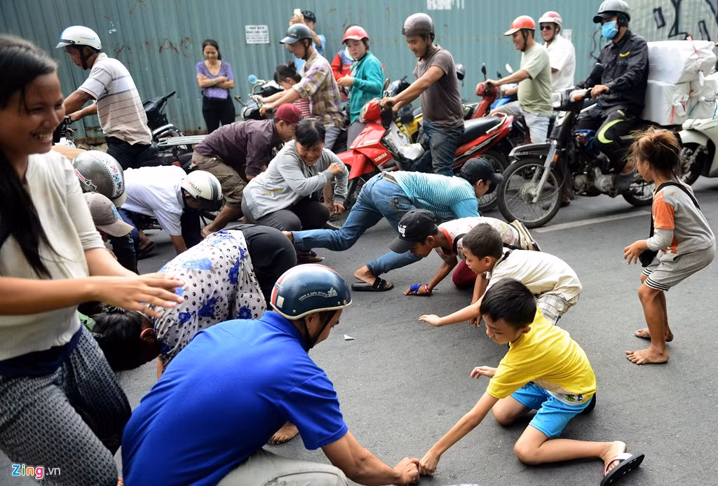 Người già, thanh niên, trẻ nhỏ lao tới tranh nhau những tờ tiền lẻ rơi xuống đất.