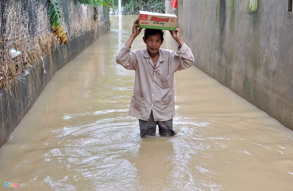 Người dân ở thôn Kim Xuyên (xã Phước Hòa, huyện Tuy Phước) lội bì bõm trong lũ ra tỉnh lộ 636B mua mì tôm ở tiệm tạp hóa về dự trữ trong những ngày ngập kéo dài.