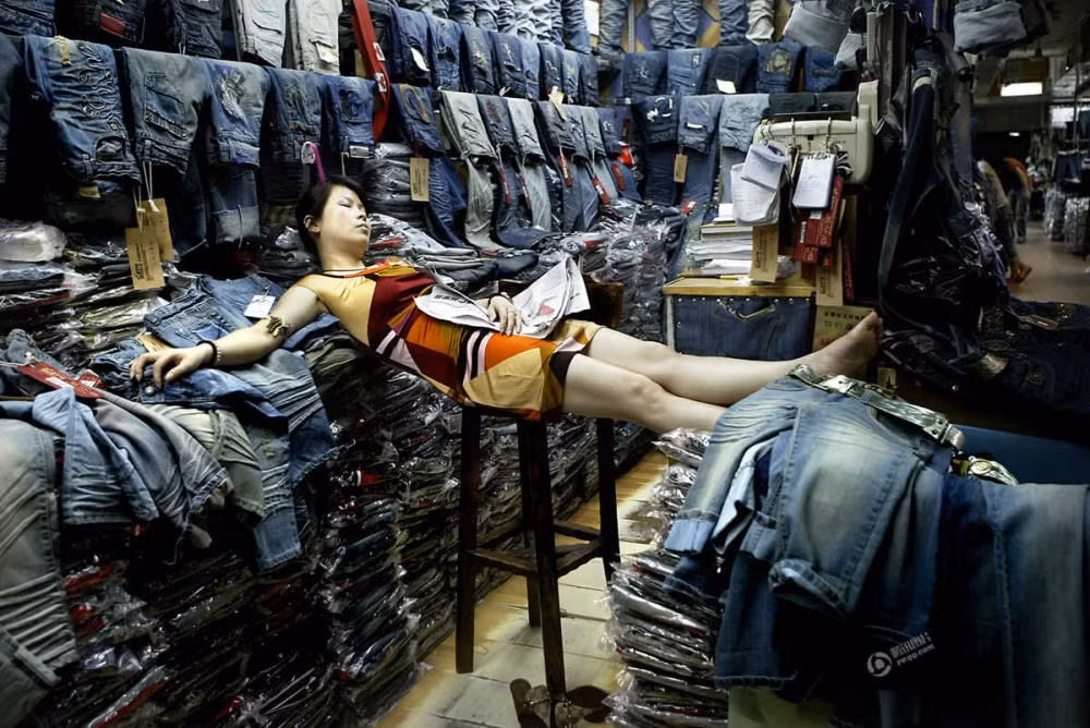 Người phụ nữ ngủ ngay tại cửa hàng của mình. (Nguồn: QQ)