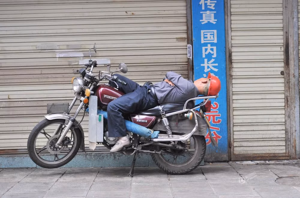 Ngủ trên xe máy. (Nguồn: QQ)