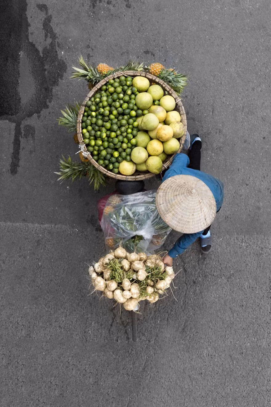 6. “Như bạn có thể tưởng tượng, Hà Nội là một thành phố sôi động và nhộn nhịp với nhiều người, nhiều xe cộ và cũng nhiều cây xanh. Nếu tôi chụp một bức ảnh từ tầm nhìn thông thường sẽ có rất nhiều thứ khác xuất hiện trong khung hình. Tôi muốn chỉ tập trung vào người phụ nữ và những gánh hàng rong “.