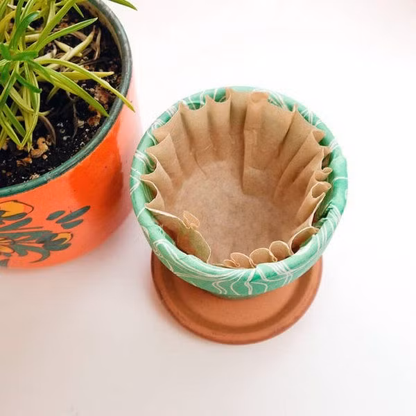 Sử dụng túi lọc trà, cà phê Túi lọc trà, cà phê được đặt phía đáy chậu có tác dụng giữ lại chất dinh dưỡng và đất không bị trôi theo nước ra ngoài. Đây cũng là cách vô cùng hữu hiệu cho những chậu cây gia vị không phải bổ sung quá nhiều chất dinh dưỡng mà cây vẫn luôn xanh tươi.