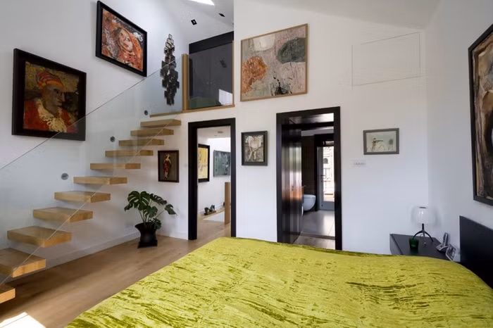 Giường ngủ được đặt ngay chân cầu thang với màu sắc tương đồng mang lại vẻ đẹp tự nhiên cho căn phòng.