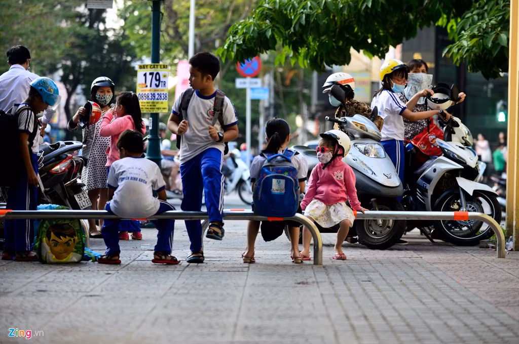 Nhiều em nhỏ tận dụng thanh barie làm chỗ ngồi chờ phụ huynh đến rước.