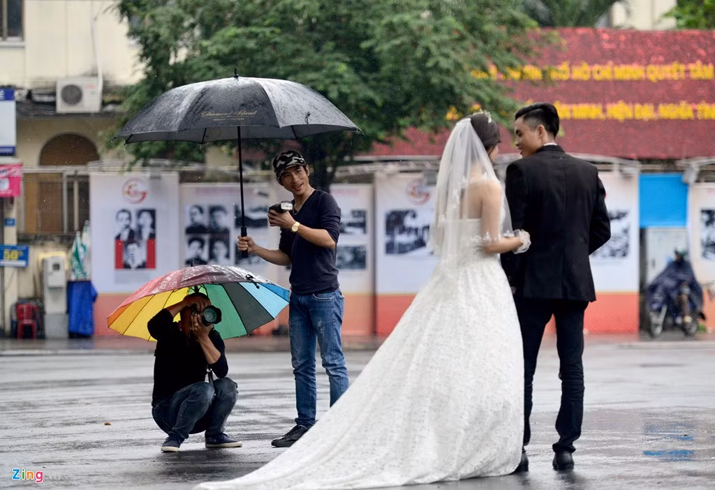 Cặp cô dâu-chú rể cùng thợ chụp ảnh say sưa tạo dáng, chụp hình giữa trời mưa trước nhà thờ Đức Bà.
