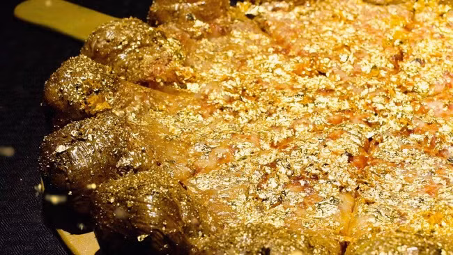 1. Pizza rắc vàng Chiếc Pizza đắt nhất thế giới mang tên Pizza Royale 007 do đầu bếp Dominico Crolla chính ta chế tạo. Nhân bánh bao gồm một con tôm hùm ướp rượu cô-nhắc, trứng cá muối ngâm sâm panh, nước sốt cà chua, cá hồi hun khói, chân giò xông khói, thịt nai, giấm thơm và đặc biệt nhất chính là những mảnh vàng 24 karat ăn được. Món ăn xa xỉ này được bán đấu giá trên trang mua sắm trực tuyến và đạt kỉ lục 4.200 USD (93 triệu VND).