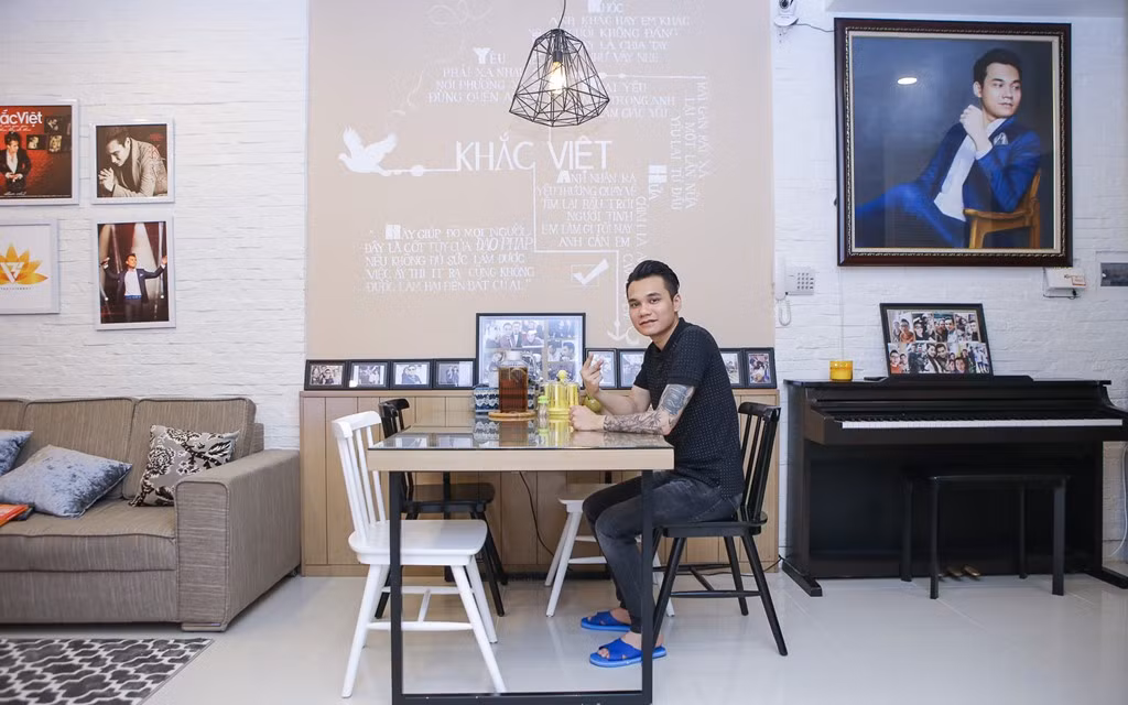 Để tiết kiệm không gian, phòng khách và bàn ăn được thiết kế liền kề nhau. Ở khu vực này, anh đặt họa sĩ vẽ lên tường các ca khúc mình từng thể hiện thành công như một điểm nhấn. Bức tranh chân dung được Khắc Việt yêu thích bởi đường nét tinh tế không khác gì ảnh chụp.