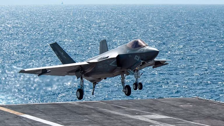 Cận cảnh một tiêm kích hạm F-35C hạ cánh với móc cáp hãm đà ở đuôi máy bay đã được bung ra, có thể thấy càng trước của máy bay sử dụng bánh kép, trong khi các phiên bản khác của F-35, chỉ sử dụng một bánh đơn.