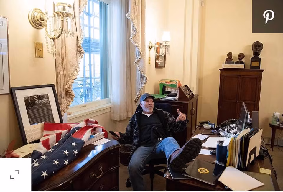Người biểu tình ủng hộ Tổng thống Donald Trump chiếm phòng Chủ tịch Hạ viện và ngồi gác chân lên bàn làm việc. Nguồn ảnh: BI.