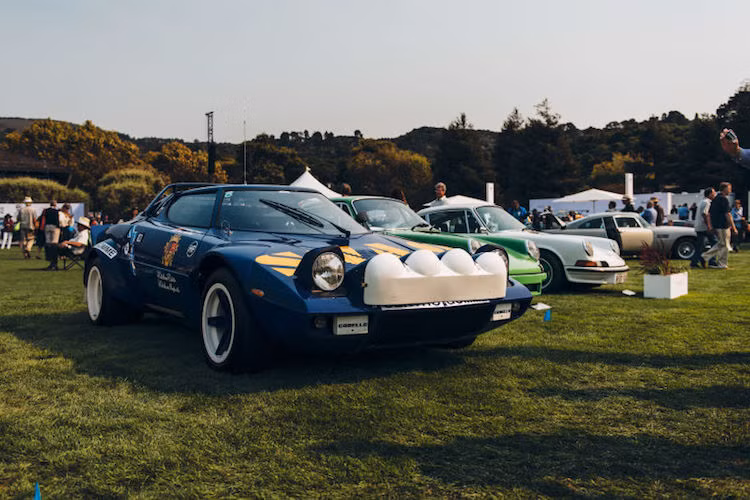 Siêu xe đua rally Lancia Stratos "so dáng" cùng 2 chiếc Porsche 911 và phía xa là chiếc Aston Martin DB5 nổi tiếng của điệp viên 007 James Bond.