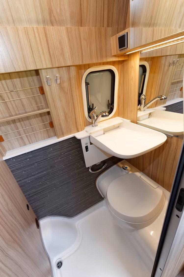 Nằm đối diện với tủ lạnh là toilet của HYMERCAR Grand Canyon S, được bố trí kín trong một diện tích nhỏ chỉ khoảng trên dưới 1m2. Tuy nhiên, toilet này cũng được ốp nhựa cùng gỗ chống nước và có đầy đủ bồn rửa mặt, bồn cầu, bình nóng lạnh, vòi hoa sen và quạt thông gió.