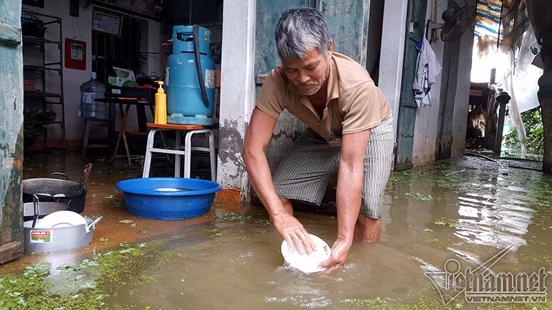 Ông Nguyễn Huy Tắc phải rửa bát đĩa bằng nước lũ trước sân nhà. Ông chia sẻ: "Nước sạch phải tiết kiệm từng giọt. Tôi rửa bát ở đây rồi mới tráng lại bằng nước sạch”