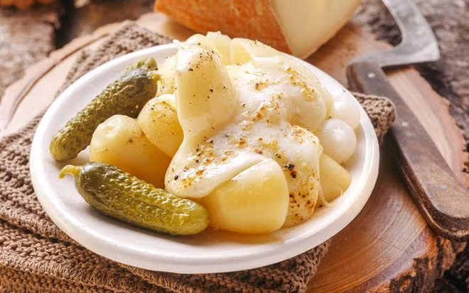 Raclette, Nam Thụy Sĩ: Đây được coi là món ăn truyền thống của Thụy Sĩ từ nhiều thế kỷ. Những người chăn cừu ở dãy Alps sưởi ấm bên bếp lửa, đun chảy một miếng phô mai, thêm khoai tây và dưa chuột muối. Ngày nay, người dân sử dụng lò nướng điện, nhưng đây vẫn là bữa ăn để nhấm nháp cùng bạn bè.